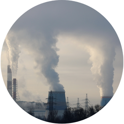 Industrial facility with large smokestacks and cooling towers emitting steam behind power lines